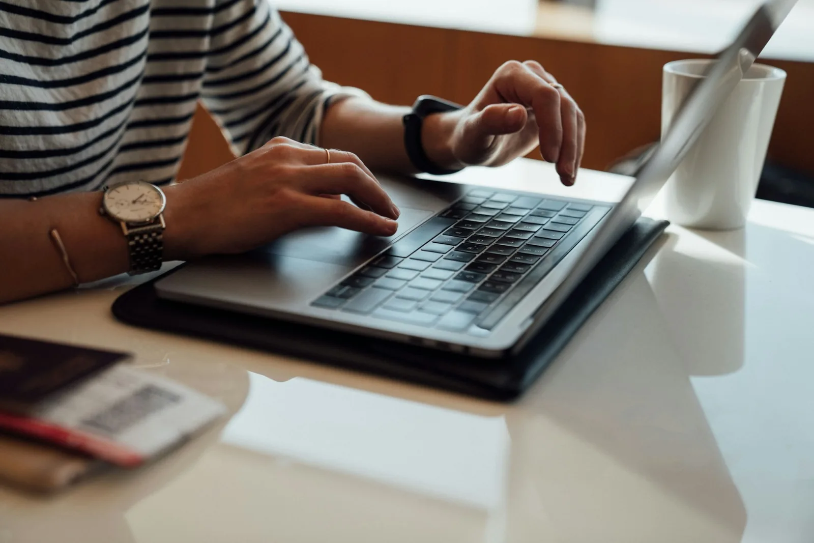 Laptopta çalışan eller, yanında pasaport ve uçak bileti