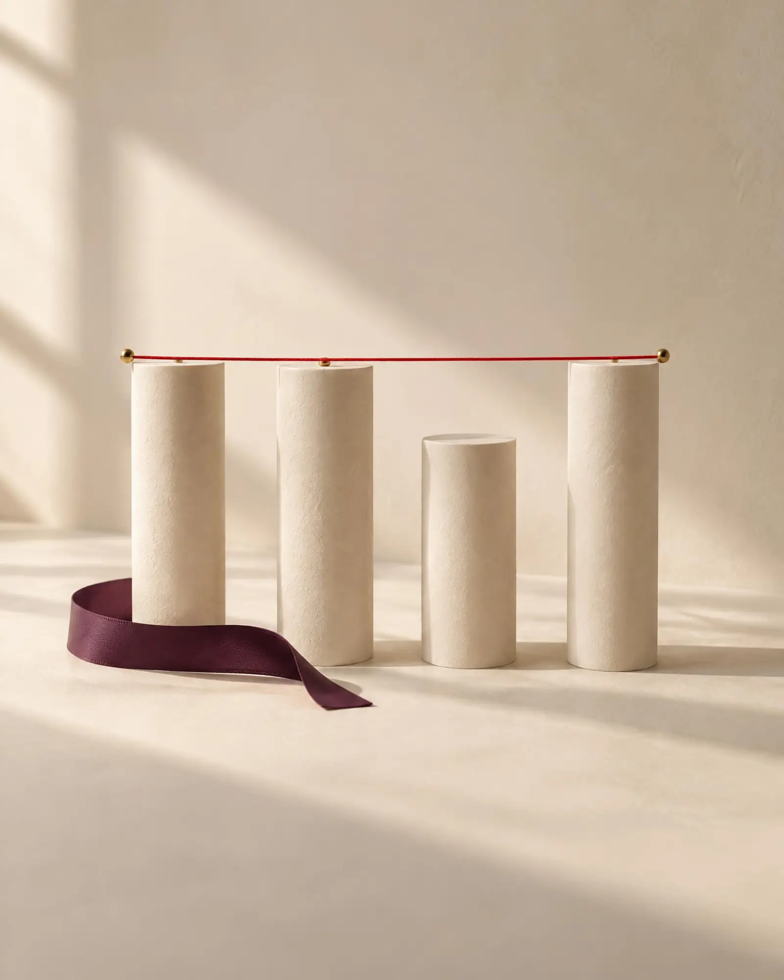 Four ivory columns beneath a taut horizontal red thread, one falling just short of the line
